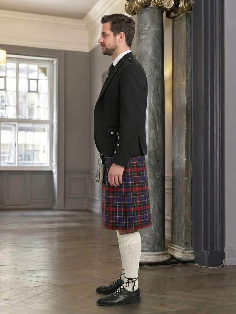 Man wearing a black jacket and red plaid kilt in an elegant interior setting.