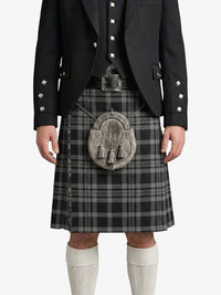 Person wearing a traditional Scottish kilt with a black jacket on a white background