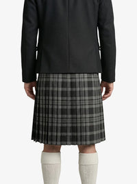 Person wearing a black coat and gray plaid kilt on a white background