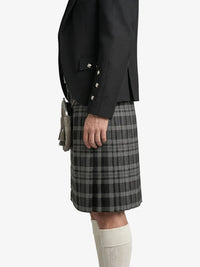Person wearing a black jacket and gray plaid kilt on a white background