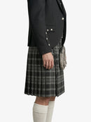 Person wearing a black jacket and plaid kilt on a white background
