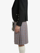 Person wearing a black jacket and plaid kilt on a white background