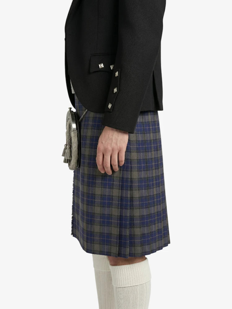 Person wearing a black jacket and plaid kilt on a white background