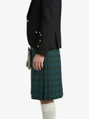 Person wearing a black jacket and green plaid kilt on a white background
