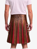 A man wearing a brown pleated leather kilt with red lining and decorative silver-tone buttons, paired with a white t-shirt, shown from the back against a light gray background.