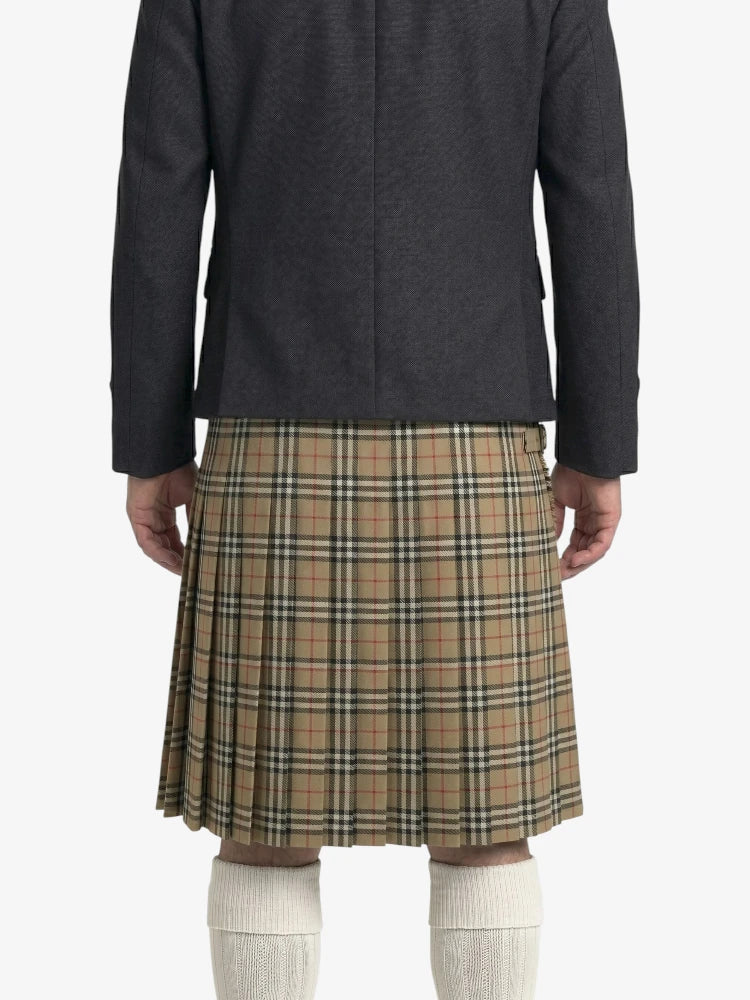 Person wearing a dark coat and plaid kilt on a white background