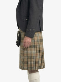 Person wearing a dark gray jacket and plaid kilt on a white background