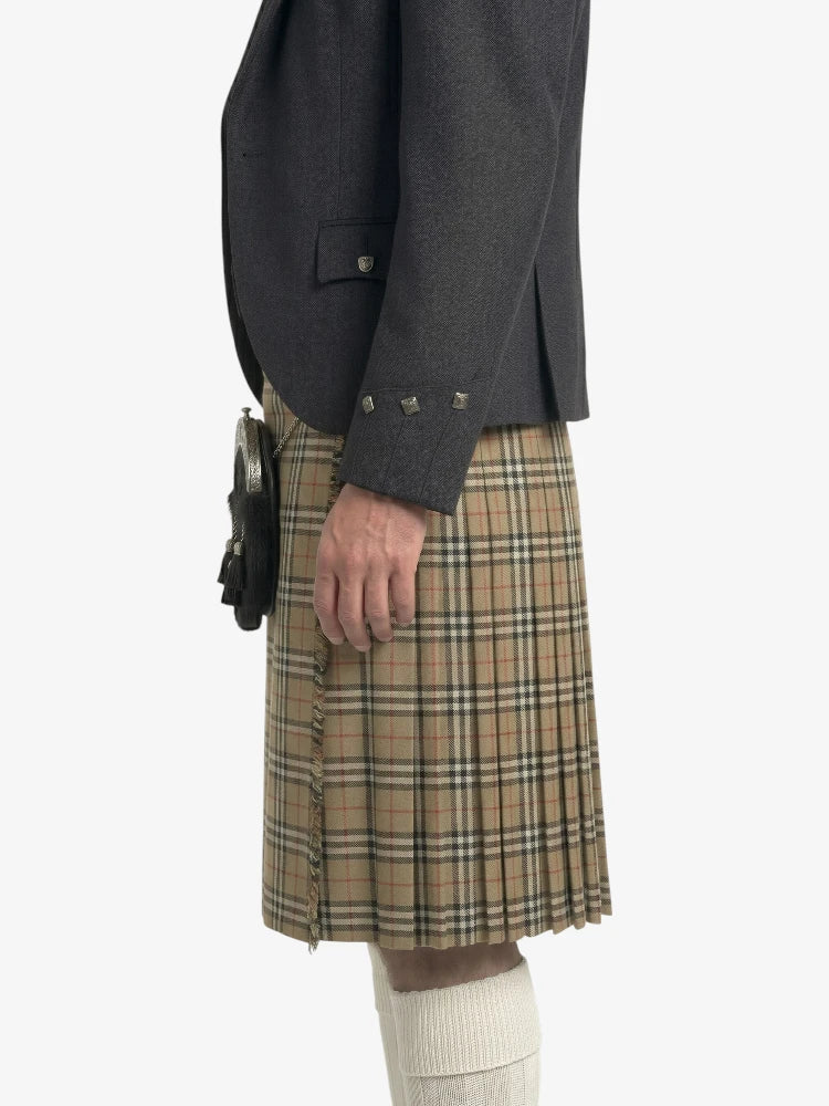 Person wearing a dark gray jacket and plaid kilt on a white background