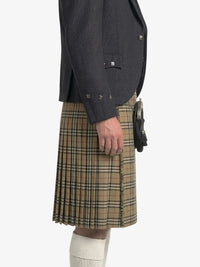 Person wearing a dark gray jacket and plaid kilt on a white background