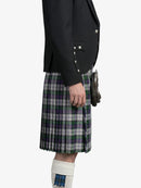 Person wearing a black jacket and plaid kilt on a white background