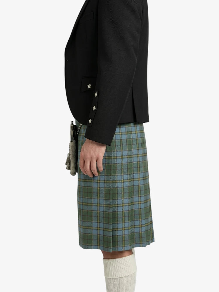 Person wearing a black jacket and green plaid kilt on a white background