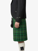 Person wearing a green plaid kilt with a black jacket on a white background