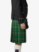 Person wearing a black jacket and green plaid kilt on a white background
