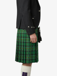 Person wearing a black jacket and green plaid kilt on a white background
