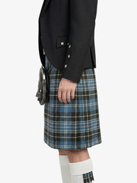 Person wearing a black jacket and plaid kilt on a white background