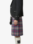 Person wearing a black blazer and plaid kilt on a white background