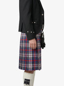 Person wearing a black jacket and plaid kilt on a white background