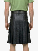 Person wearing a green shirt and black leather kilt with studded belt on a white background
