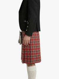Person wearing a black blazer and red plaid kilt on a white background