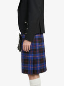Person wearing a black blazer and blue plaid kilt on a white background