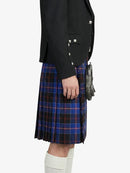 Person wearing a black blazer and blue plaid kilt on a white background