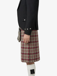 Person wearing a black jacket and plaid kilt on a white background