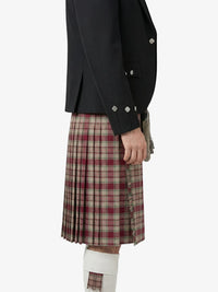 Person wearing a black jacket and plaid kilt on a white background