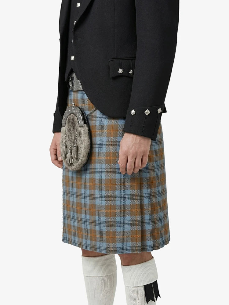 Person wearing a black jacket, plaid kilt, and white knee-high socks on a white background
