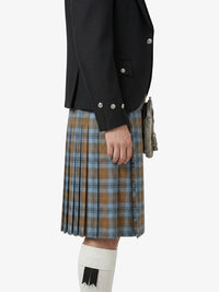 Person wearing a black jacket and plaid kilt on a white background
