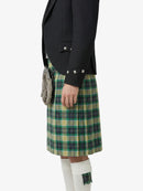 Person wearing a black blazer and green plaid kilt on a white background