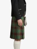 Person wearing a black jacket and green plaid kilt on a white background