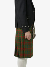 Person wearing a black jacket and green plaid kilt on a white background