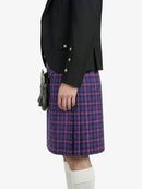 Person wearing a black jacket and purple plaid kilt on a white background