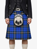 Person wearing a blue plaid kilt with a black jacket and white shirt on a white background