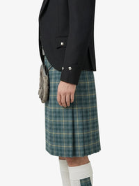 Person wearing a black blazer and green plaid kilt on a white background