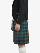 Person wearing a black jacket and plaid kilt on a white background