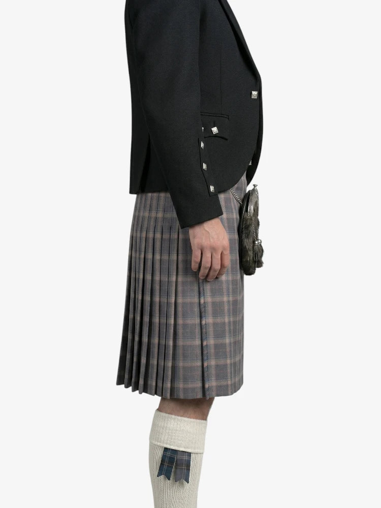 Person wearing a black jacket and plaid kilt on a white background