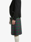 Person wearing a black jacket and plaid kilt on a white background