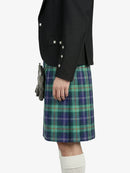 Person wearing a black jacket and green plaid kilt on a white background