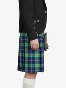 Person wearing a black jacket and green plaid kilt on a white background
