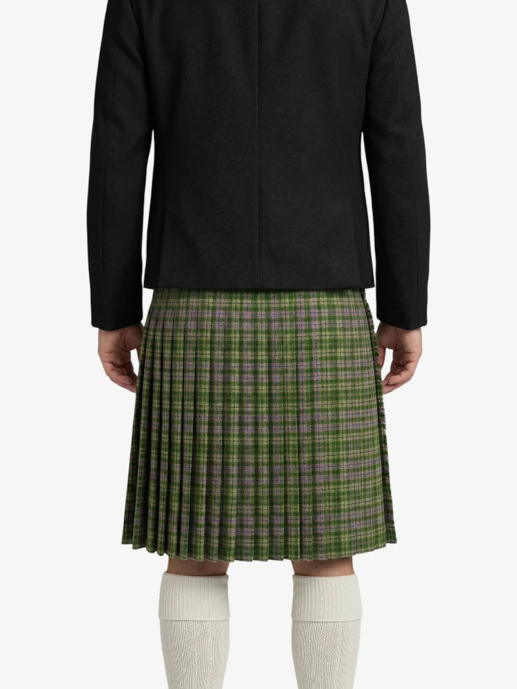 Person wearing a black jacket and green plaid kilt on a white background