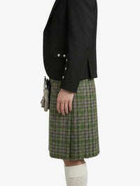 Person wearing a black blazer and green plaid kilt on a white background