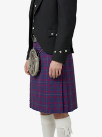 Person wearing a traditional Scottish kilt with a jacket on a white background