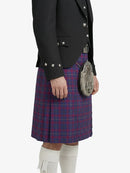 Person wearing a black jacket and red plaid kilt on a white background
