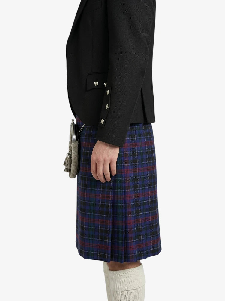 Person wearing a black blazer and plaid kilt on a white background