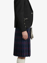 Person wearing a black blazer and plaid kilt on a white background