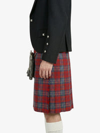 Person wearing a black blazer and red plaid kilt on a white background