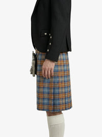 Person wearing a black blazer and plaid kilt on a white background