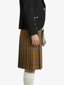 Person wearing a black jacket and plaid kilt on a white background
