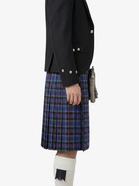 Person wearing a black jacket and blue plaid kilt on a white background